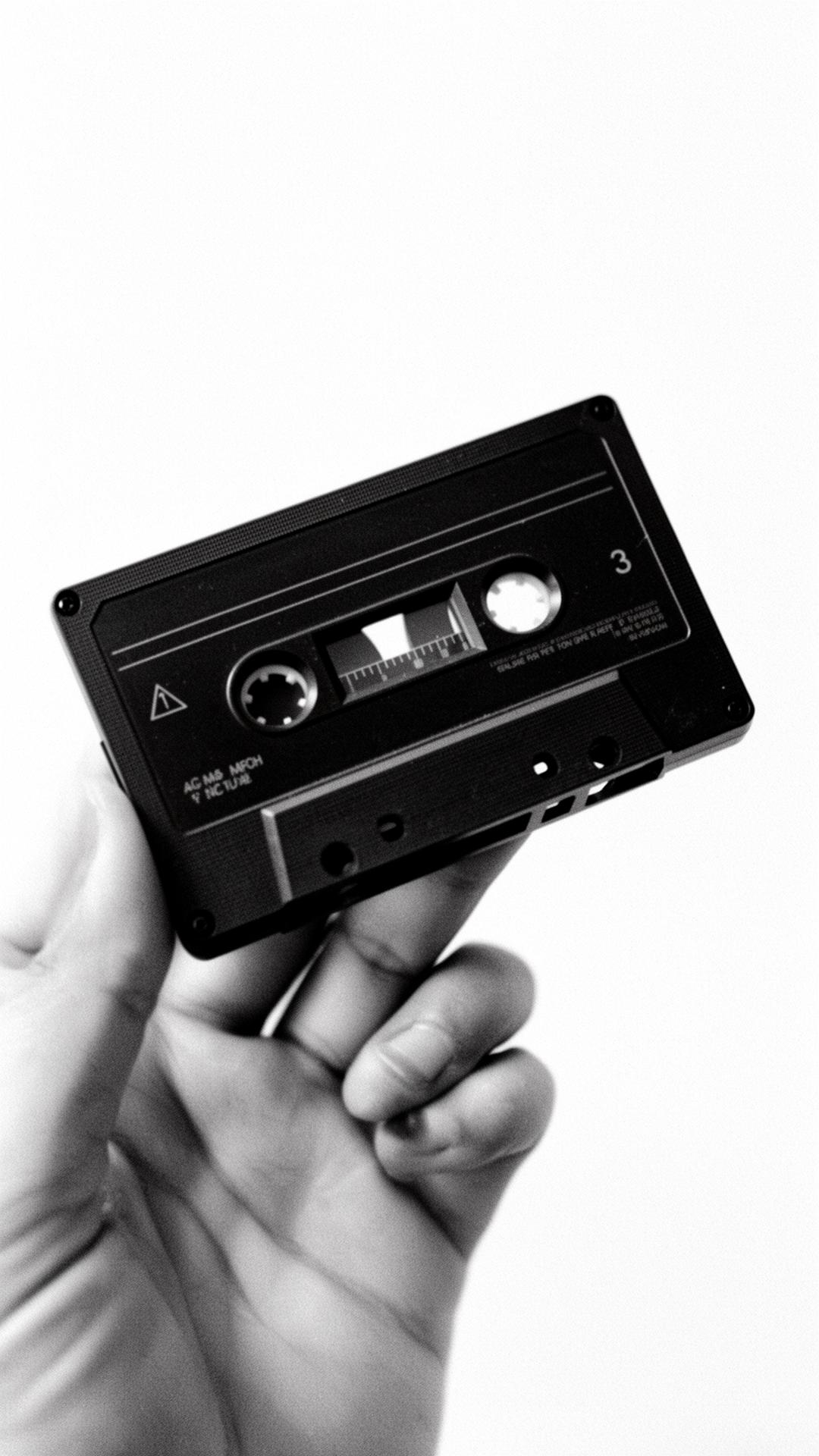 Hand holding a cassette, black and white film photo.